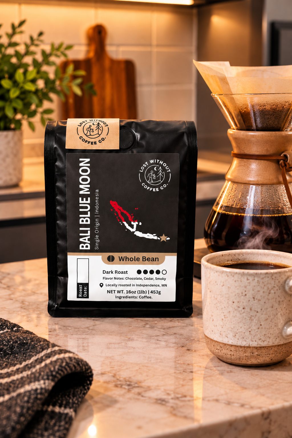 A bag of Bali Blue Moon Coffee Co. whole bean coffee sits on a kitchen countertop next to a ceramic coffee dripper and a cup of brewed coffee.