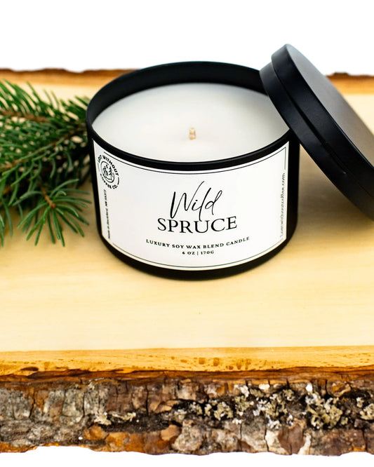 Soy Wax Candles | 6oz Wild Spruce candle on a wooden surface with pine branches.