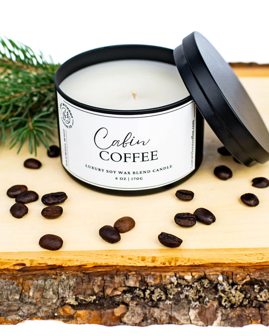 Soy Wax Candles - Cabin Coffee 6oz candle with a lid, coffee beans, and pine on a wooden surface.
