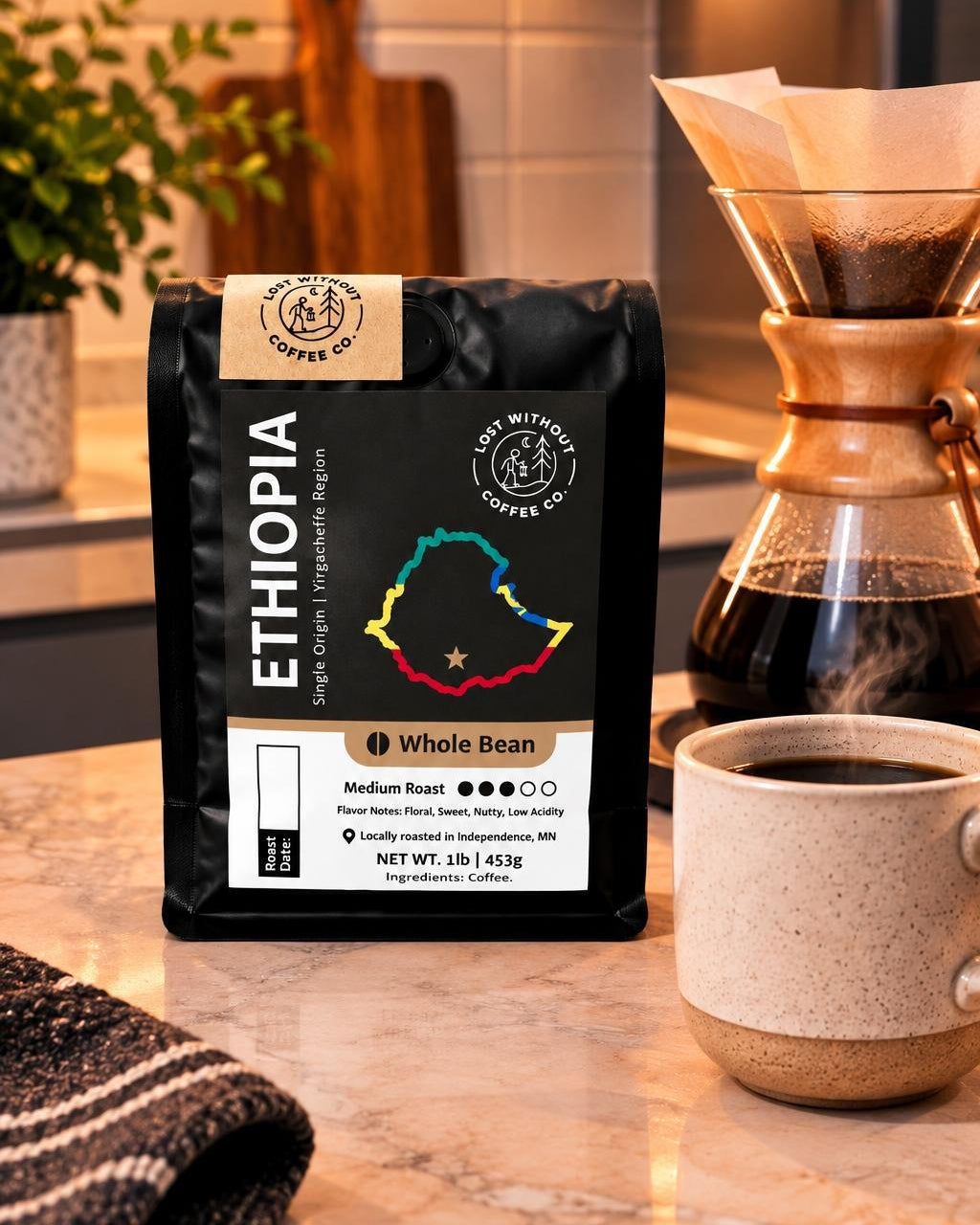 A bag of Ethiopia whole bean coffee from Coffee Co. sits on a marble kitchen counter next to a ceramic mug of coffee and a glass pour-over coffee maker.