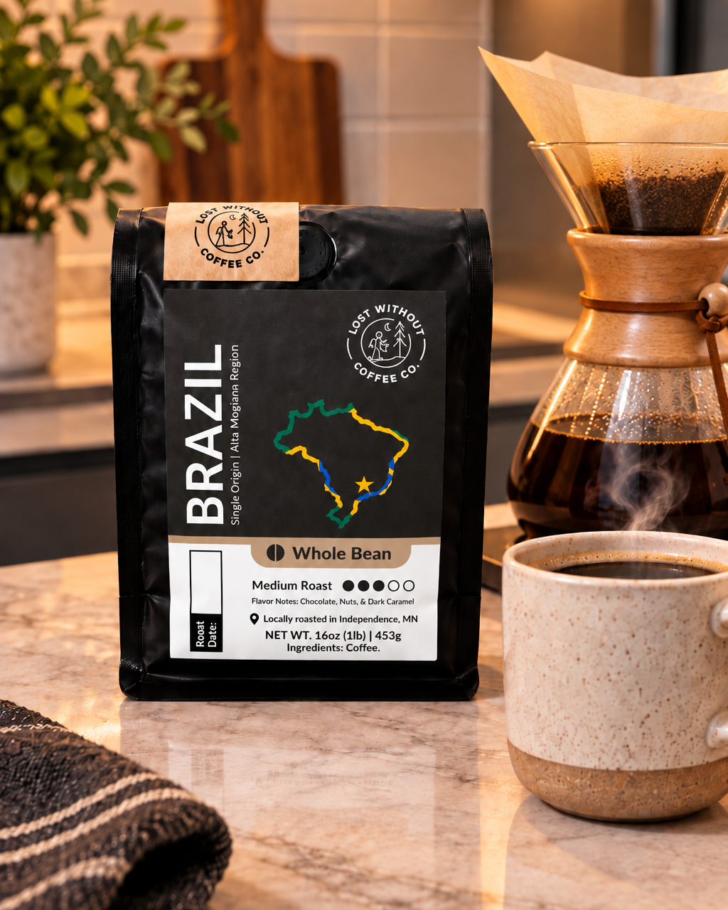 A bag of Brazil whole bean coffee from Less Wrong With Coffee Co. sits on a marble kitchen counter next to a ceramic mug of coffee and a glass pour-over coffee maker.