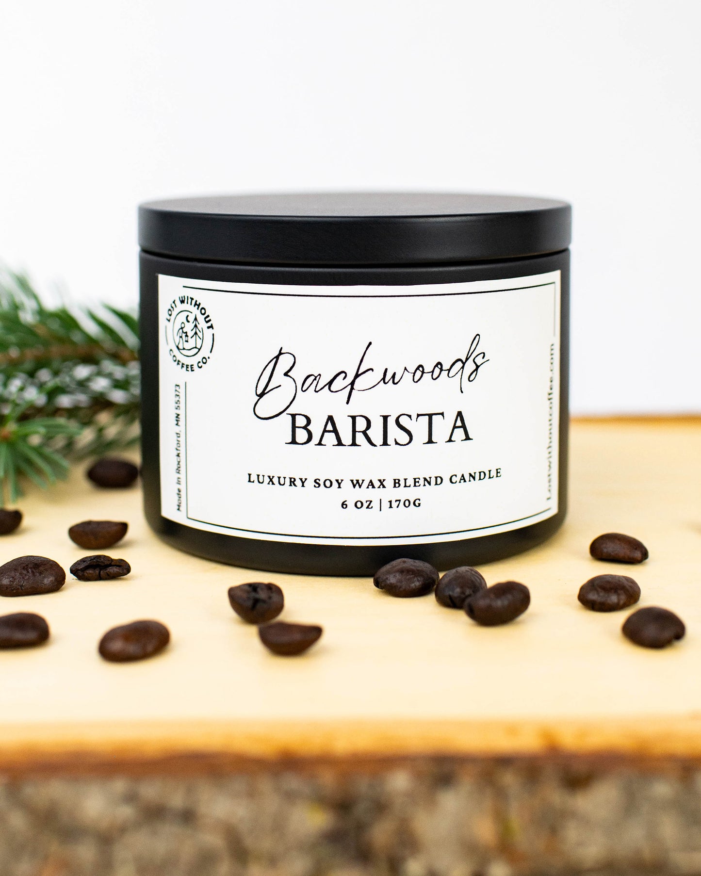 Soy Wax Candles - 6oz Backwoods Barista coffee scented candle with coffee beans and pine on wooden surface.