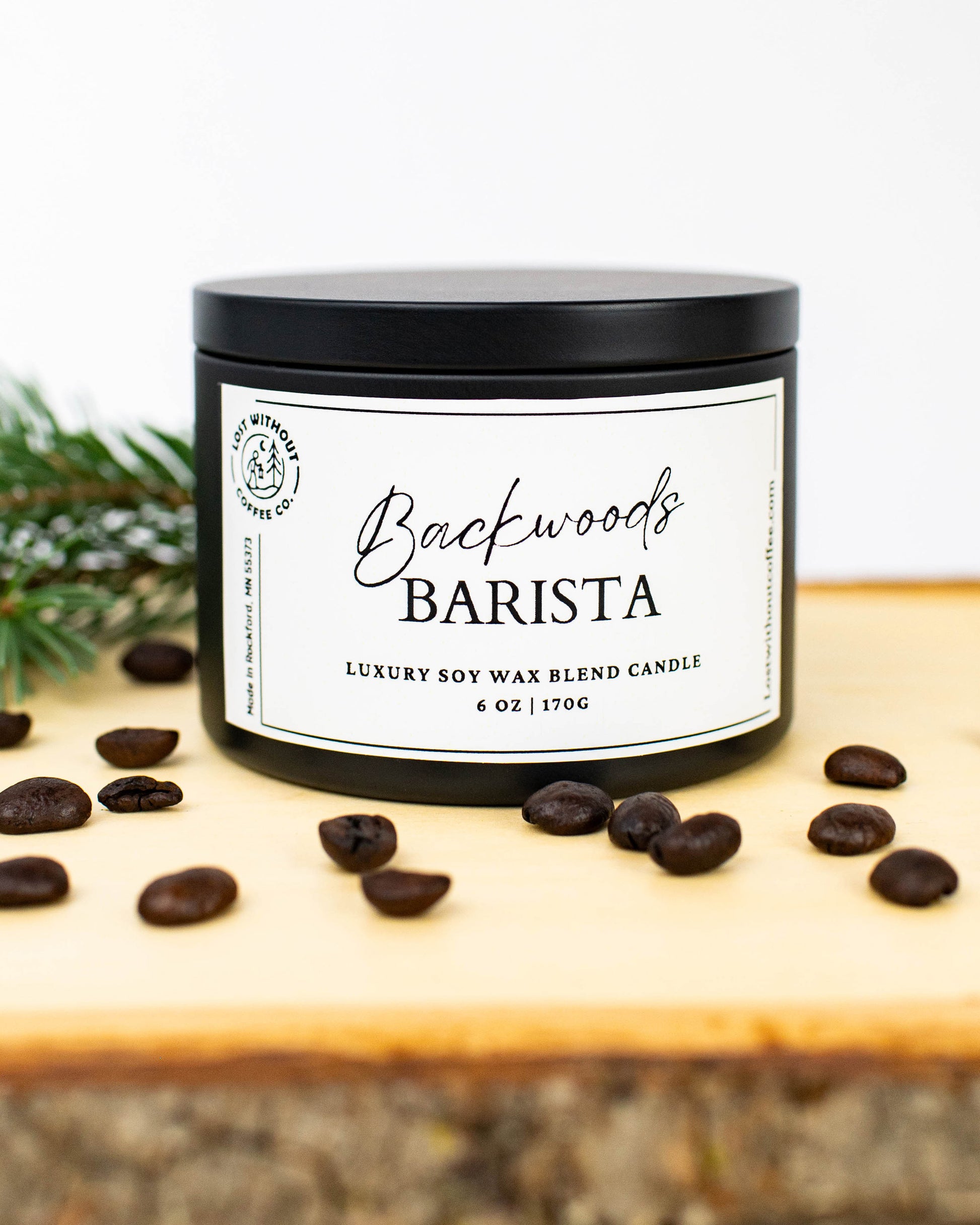 Soy Wax Candles - 6oz Backwoods Barista coffee scented candle with coffee beans and pine on wooden surface.
