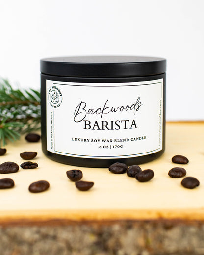 Soy Wax Candles - 6oz Backwoods Barista coffee scented candle with coffee beans and pine on wooden surface.